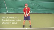 A tennis player stands at the baseline holding the racket in front of him with both hands.