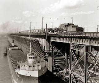 Black and white photo of a ship at an iron ore docks.