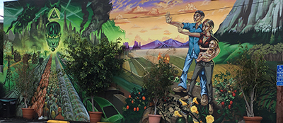 A mural with a man and a woman holding a baby in the field.