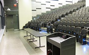 A view of the lecture hall from the back left corner of the room, looking down toward the lectern and chalkboards.