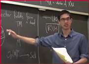 A men standing in front of a blackboard and pointing the blackboard with right hand.