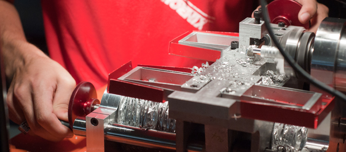 A student working a piece of metal in a lathe.