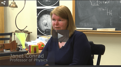 Woman sitting in front of a blackboard and talking.