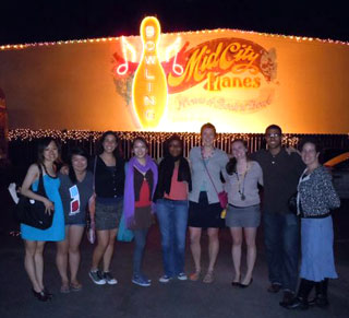 Eight students pose in front of a bowling alley.