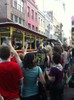 A trolley drives down a street crowded with people during a parade.