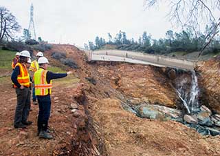 A photo of a group of construction workers standing on the edge of a ditch.