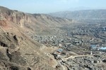 A built up town in an arid valley surrounded by mountains.