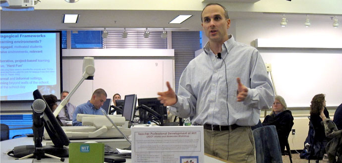 A man standing with a classroom full of people in the background.