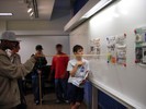 A newspaper is hung on a wall, and a student tries to read the text from a distance.